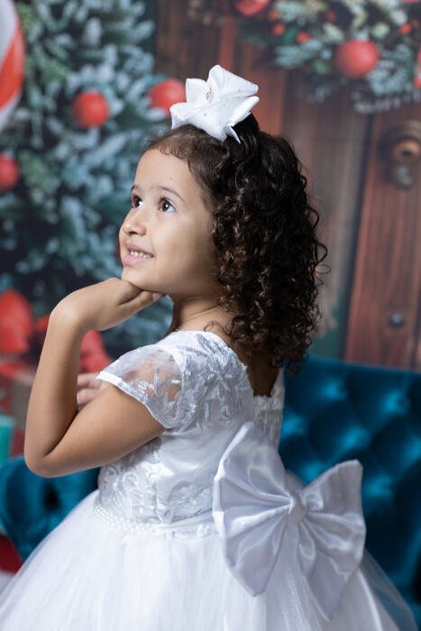 Menina de vestido branco no cenário de Natal